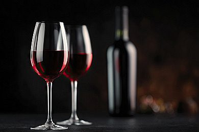 Two glasses of red wine and a bottle on a black background